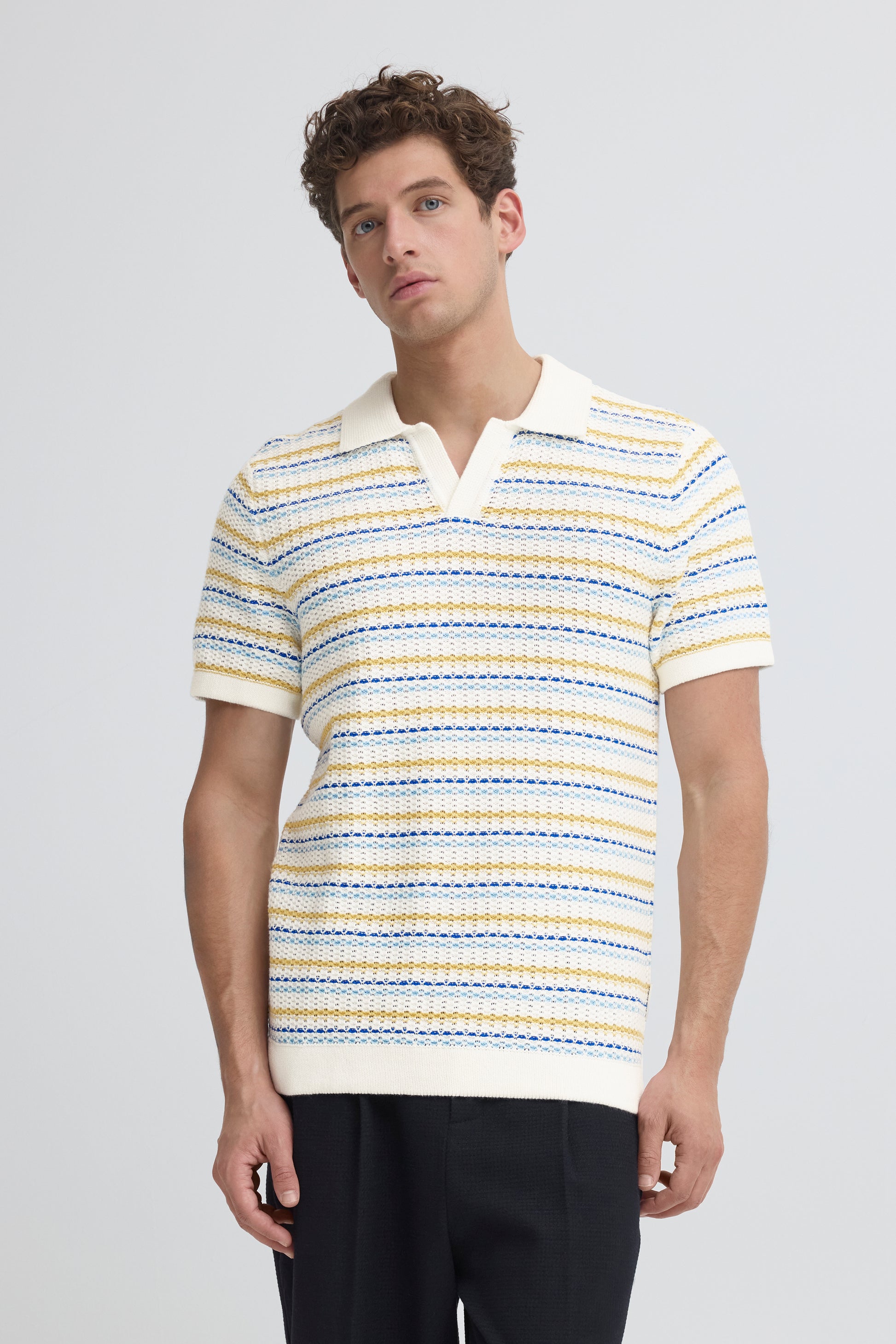 Man wearing a striped polo shirt against a plain background