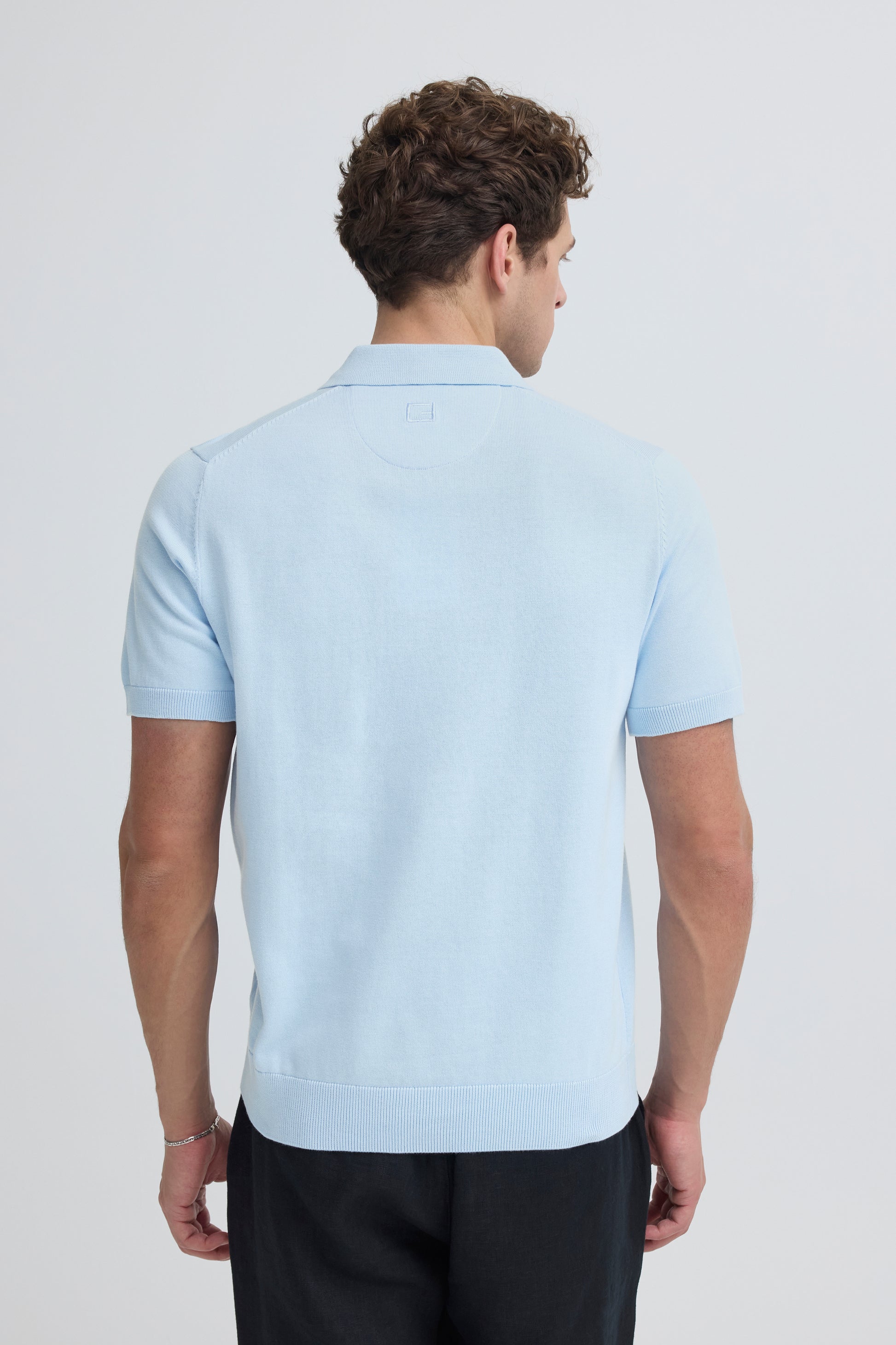 Man wearing a light blue polo shirt on a plain background