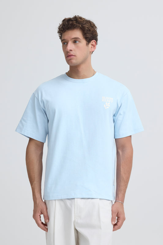 Man wearing a light blue t-shirt and beige pants on a plain background