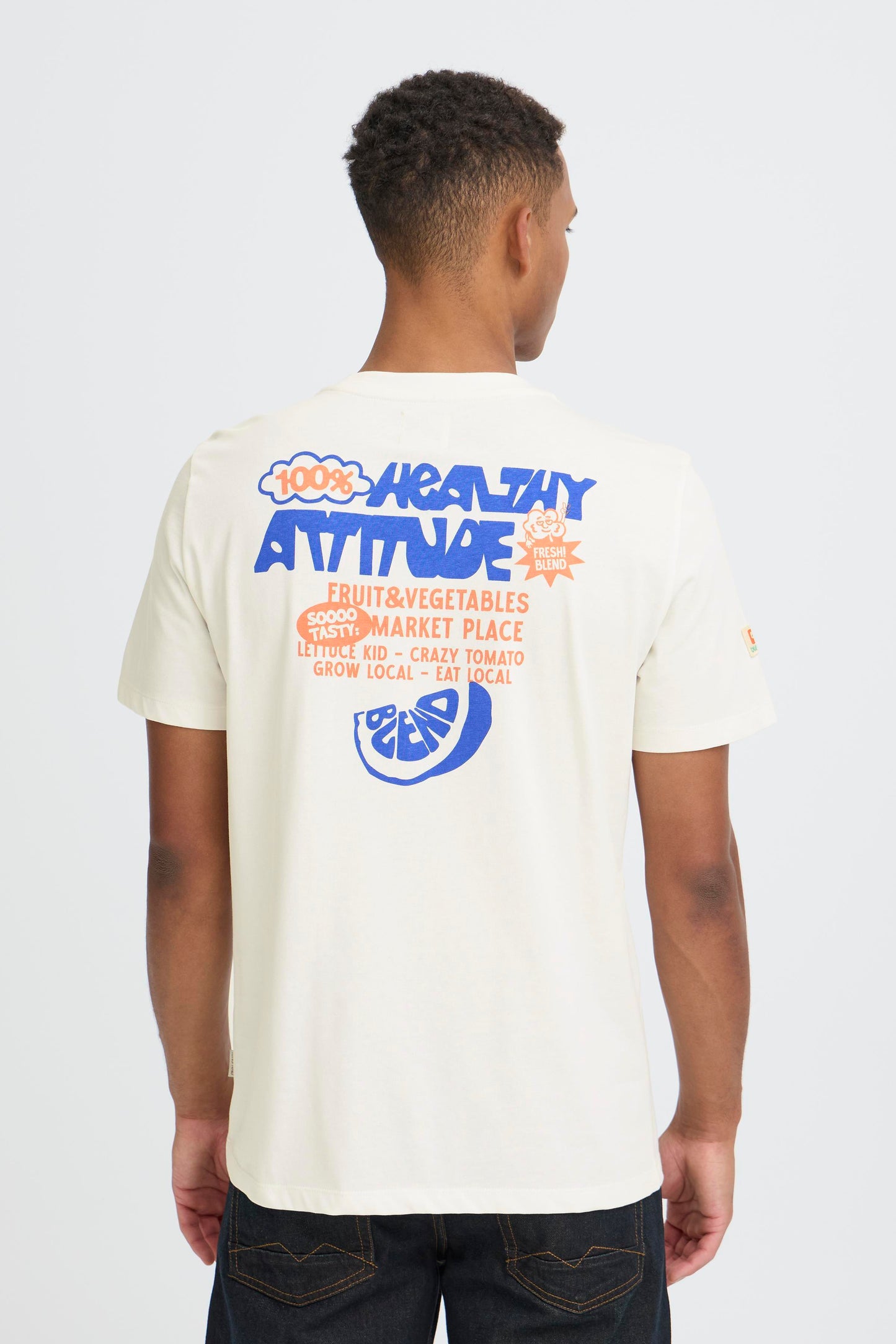 Person wearing a white t-shirt with colorful graphics and text on the back, standing against a plain background.