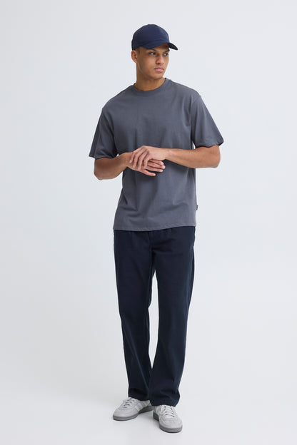 Person wearing a gray t-shirt, navy cap, and dark pants on a white background
