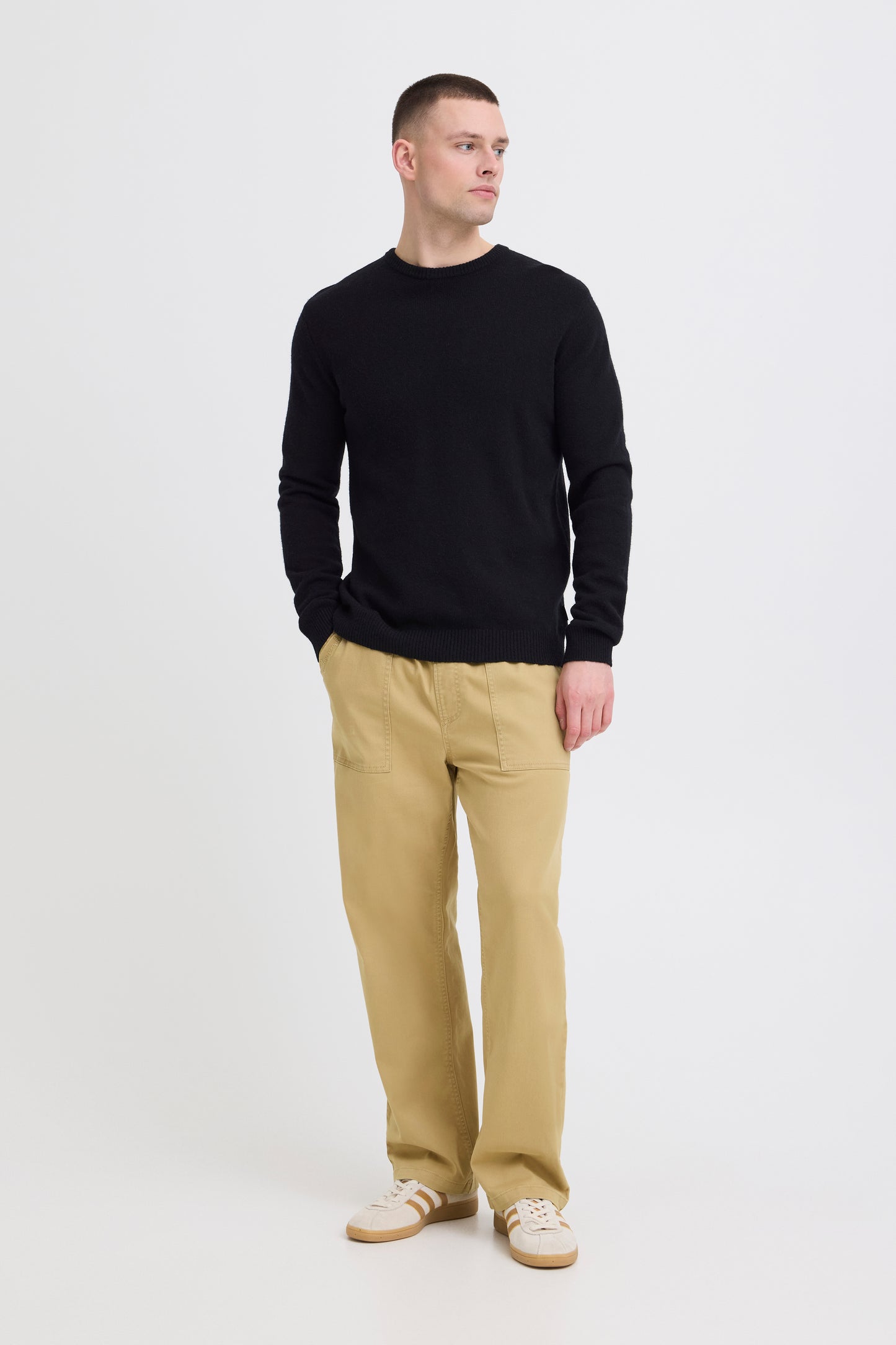 Man wearing a black sweater and beige pants on a white background