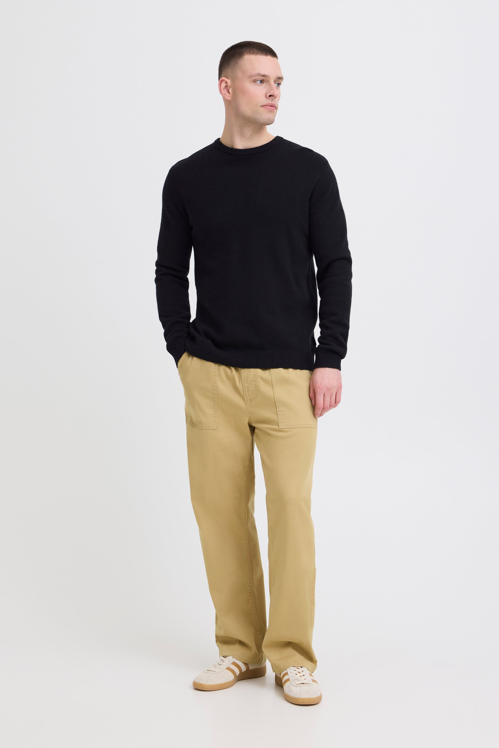 Man wearing a black sweater and beige pants on a white background