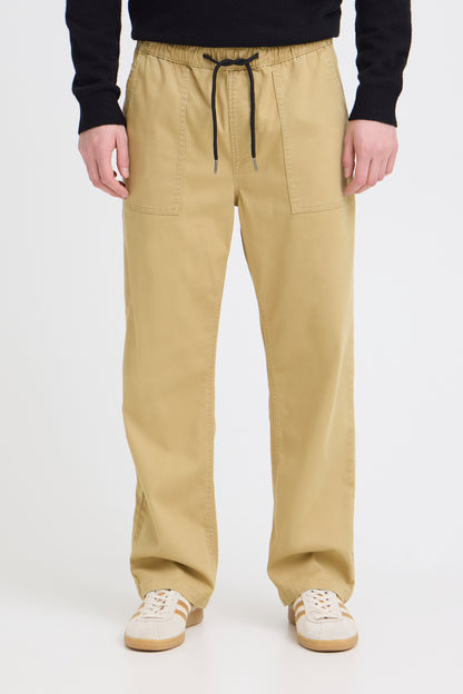 Person wearing beige pants with a black drawstring on a white background
