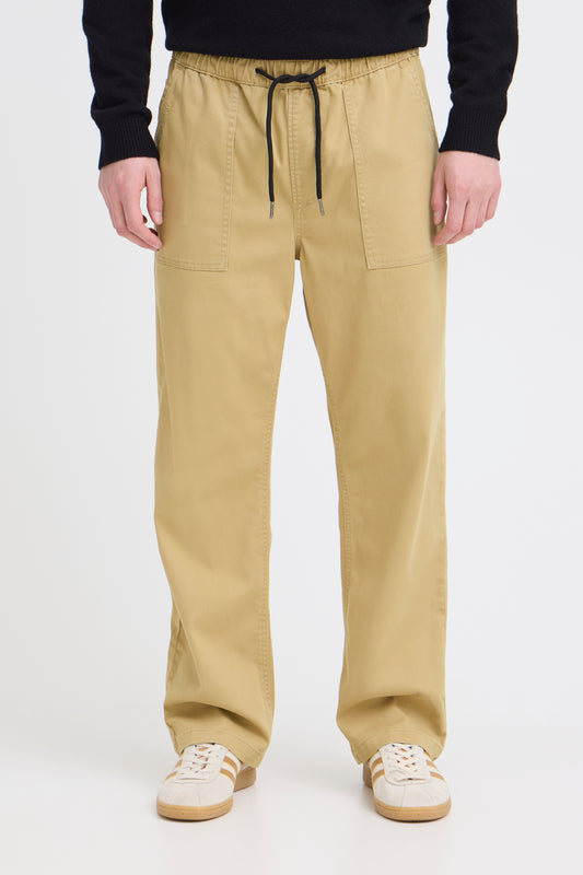 Person wearing beige pants with a black drawstring on a white background