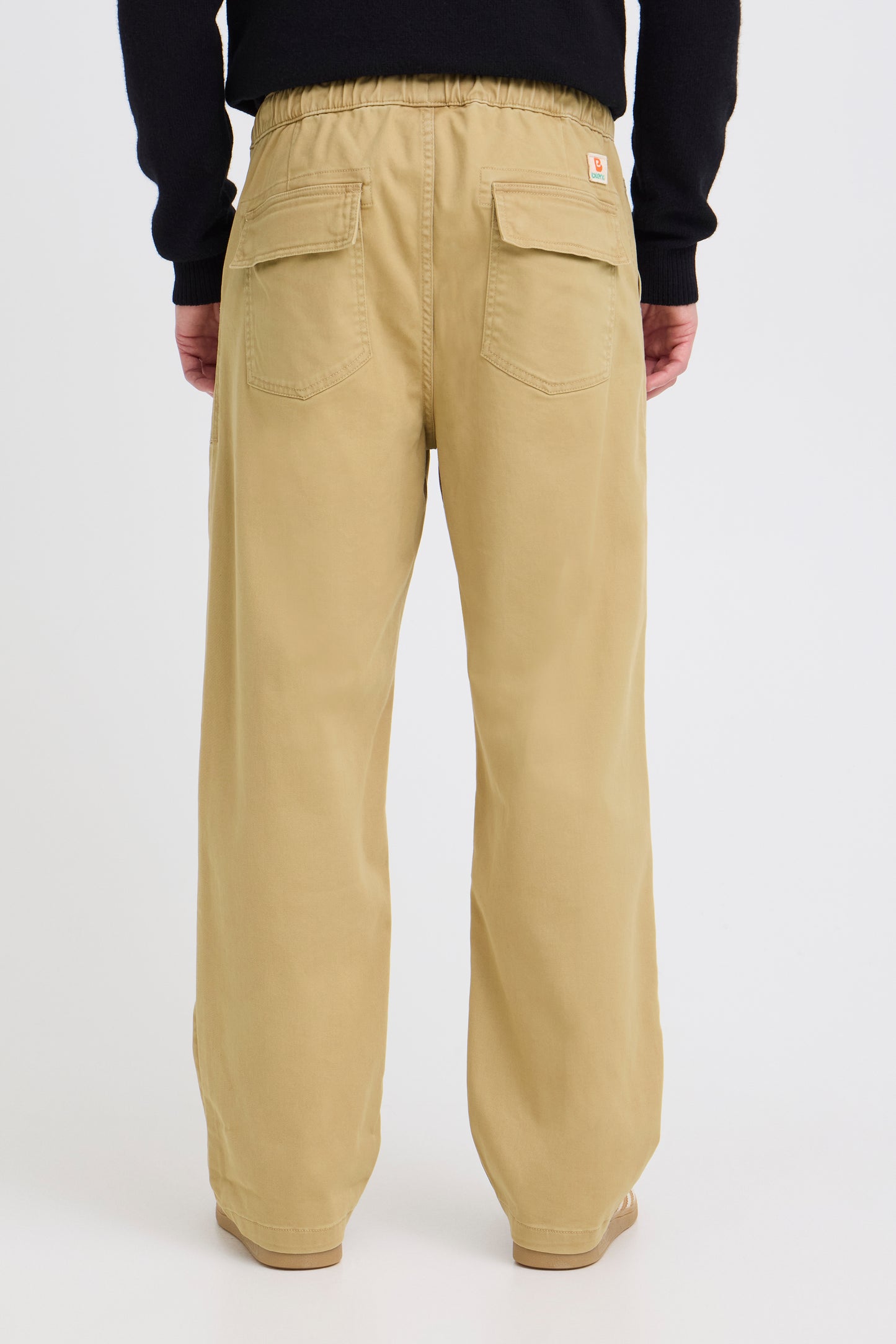 Beige pants worn by a person on a white background
