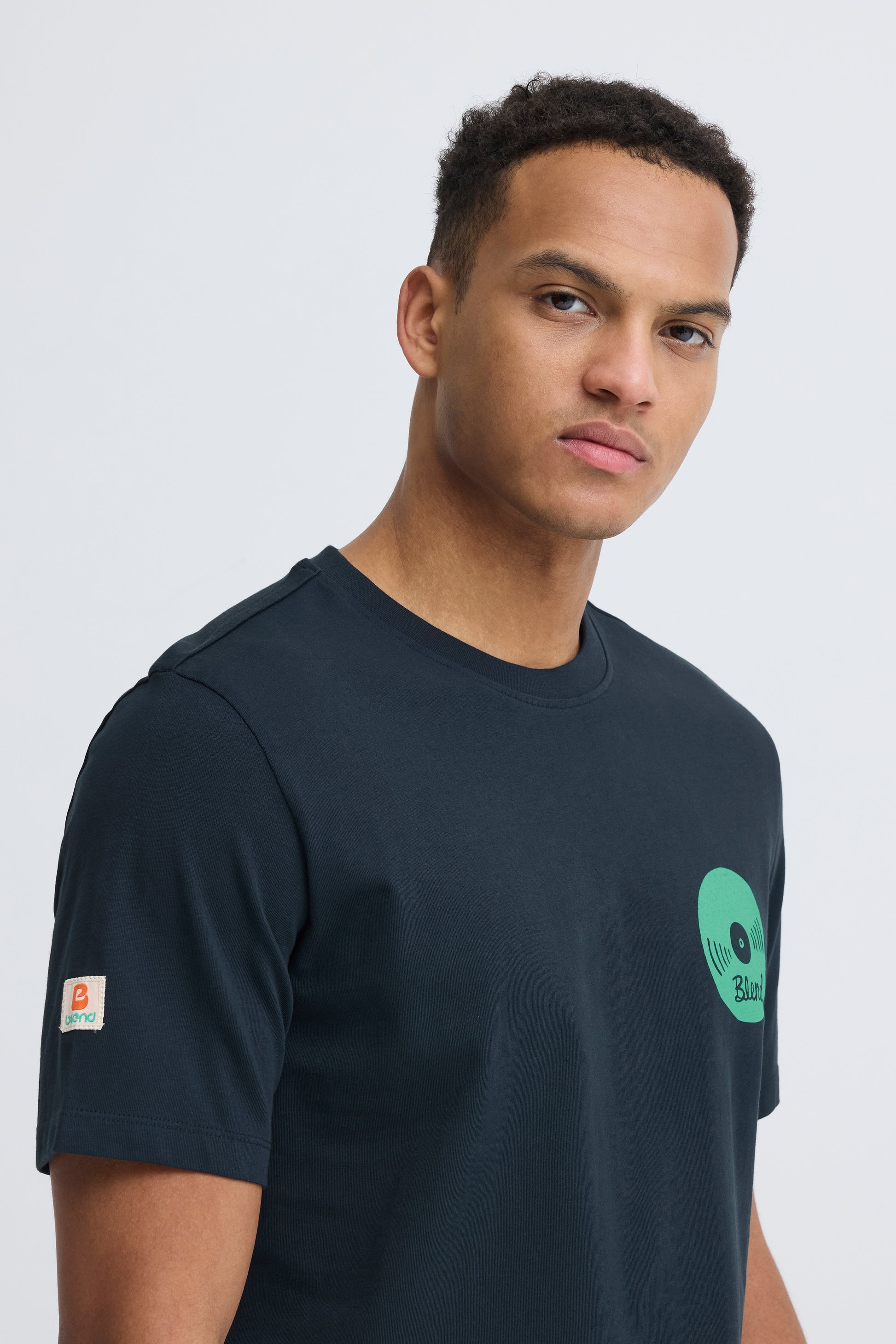 Man wearing a black t-shirt with a green logo on a white background