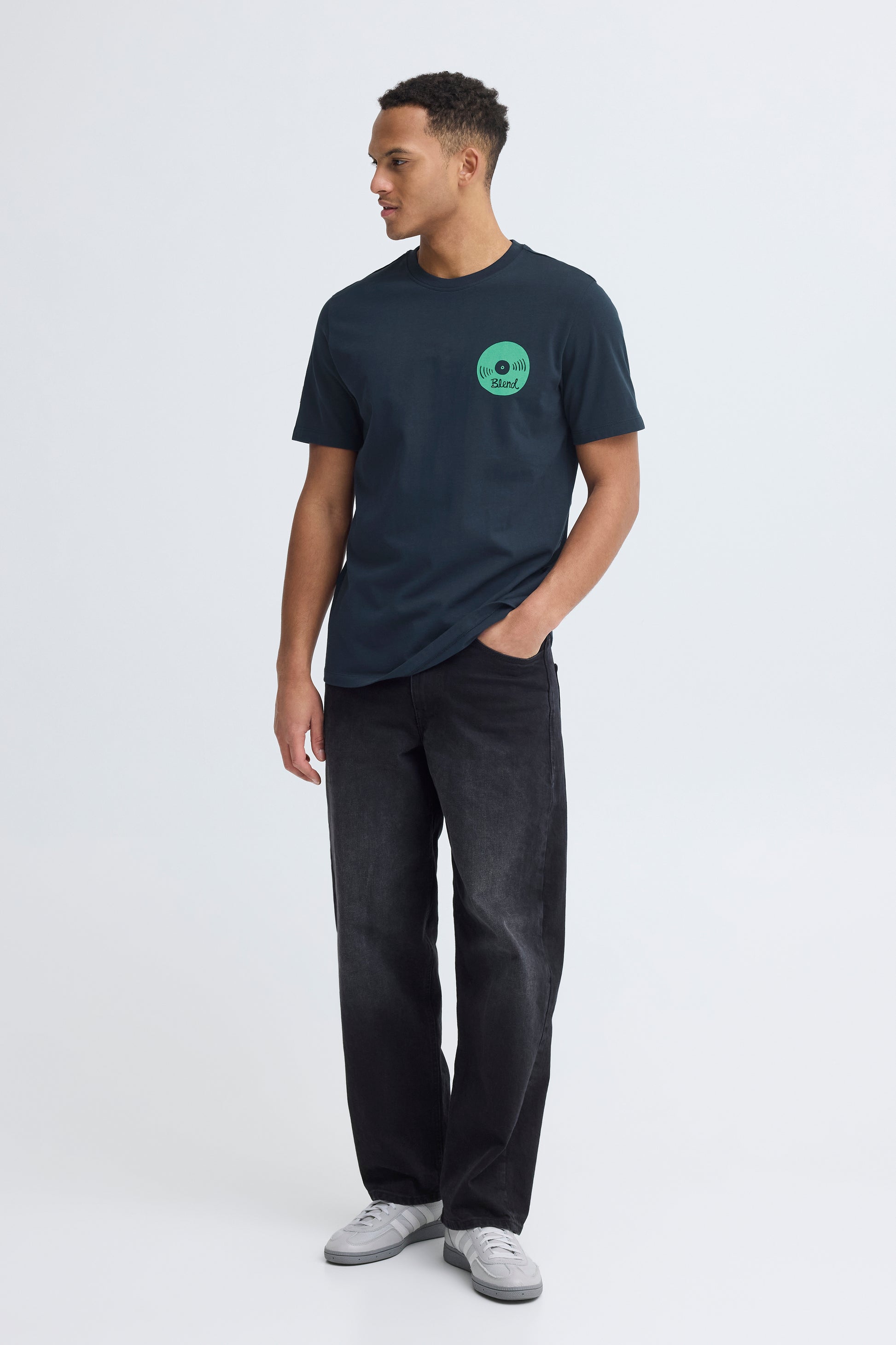 Man wearing a dark blue t-shirt with a green logo on a white background