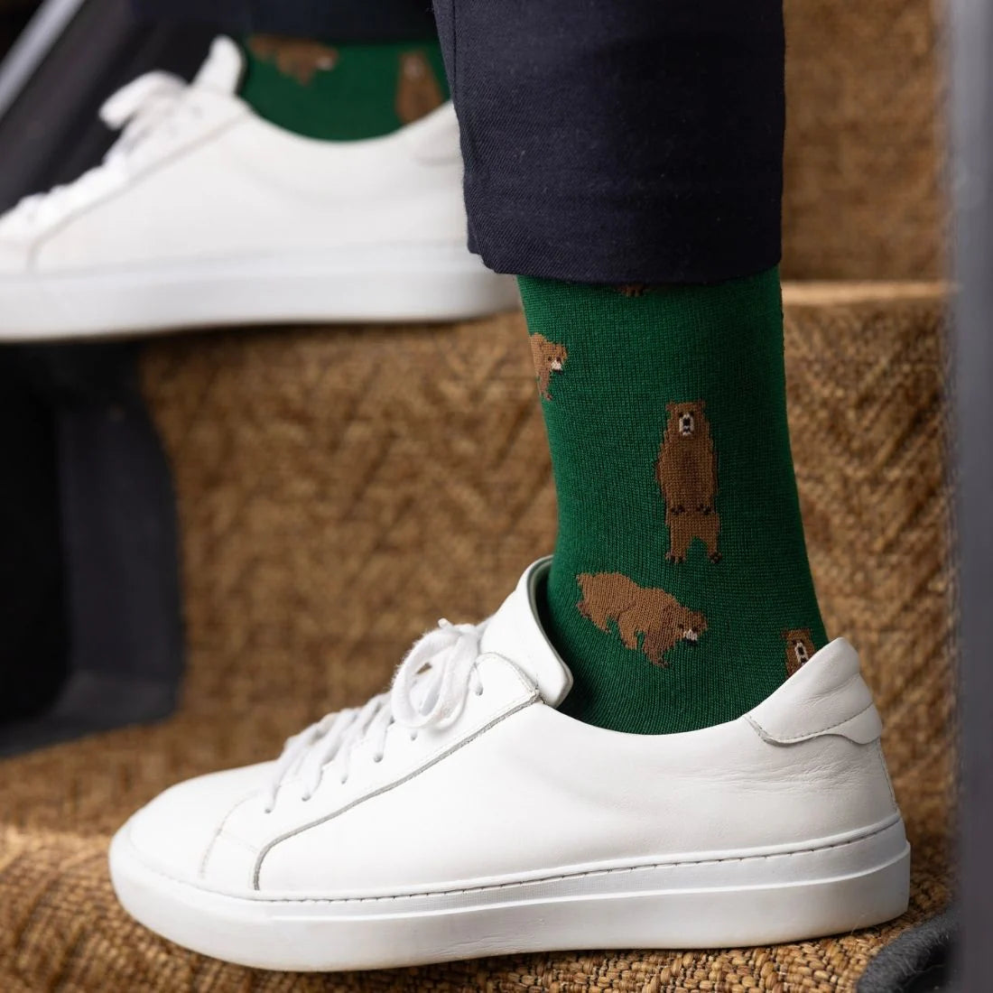 Green socks with bear pattern worn with white sneakers on a blurred background