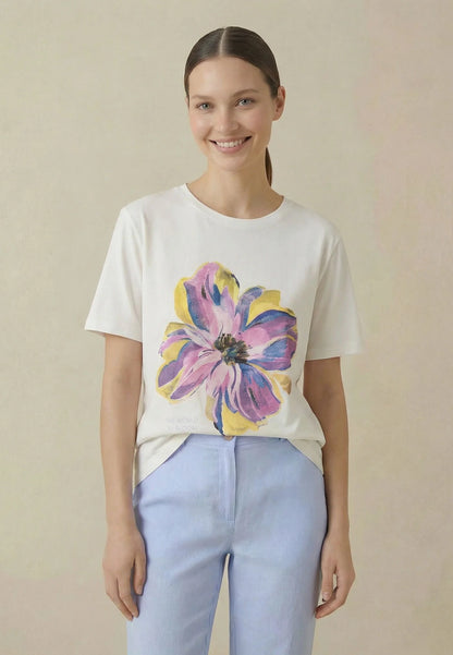 Woman wearing a white t-shirt with a colorful flower design on a beige background