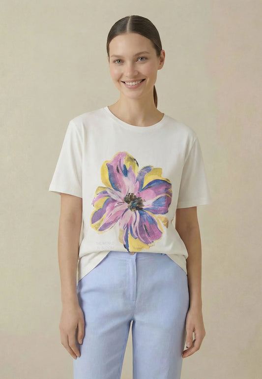 Woman wearing a white t-shirt with a colorful flower design on a beige background
