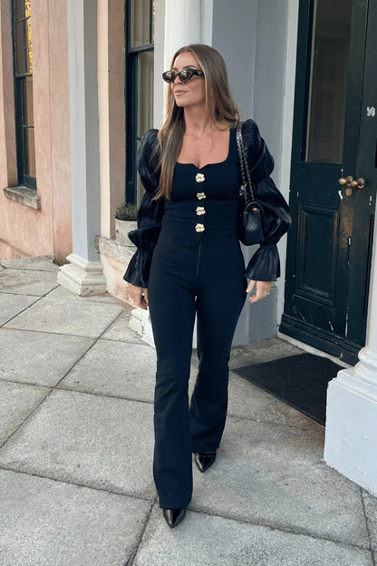 Woman in a black outfit walking outside a building