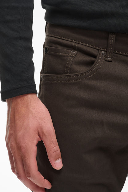 Close-up of a person wearing dark brown or very deep olive trousers, showing the side pocket, belt loop, waistband, and hand resting near the leg.