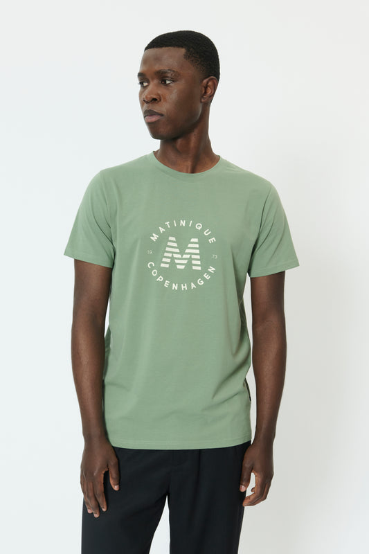 Man wearing a green t-shirt with a logo on a white background