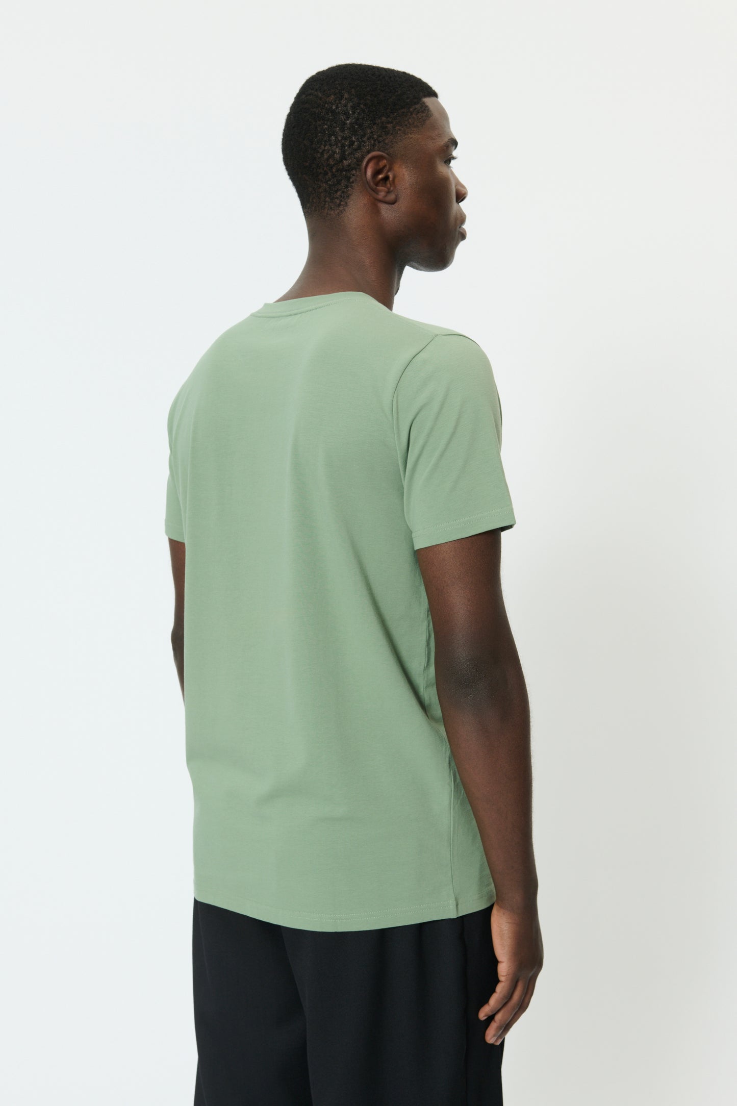 Person wearing a light green t-shirt on a white background