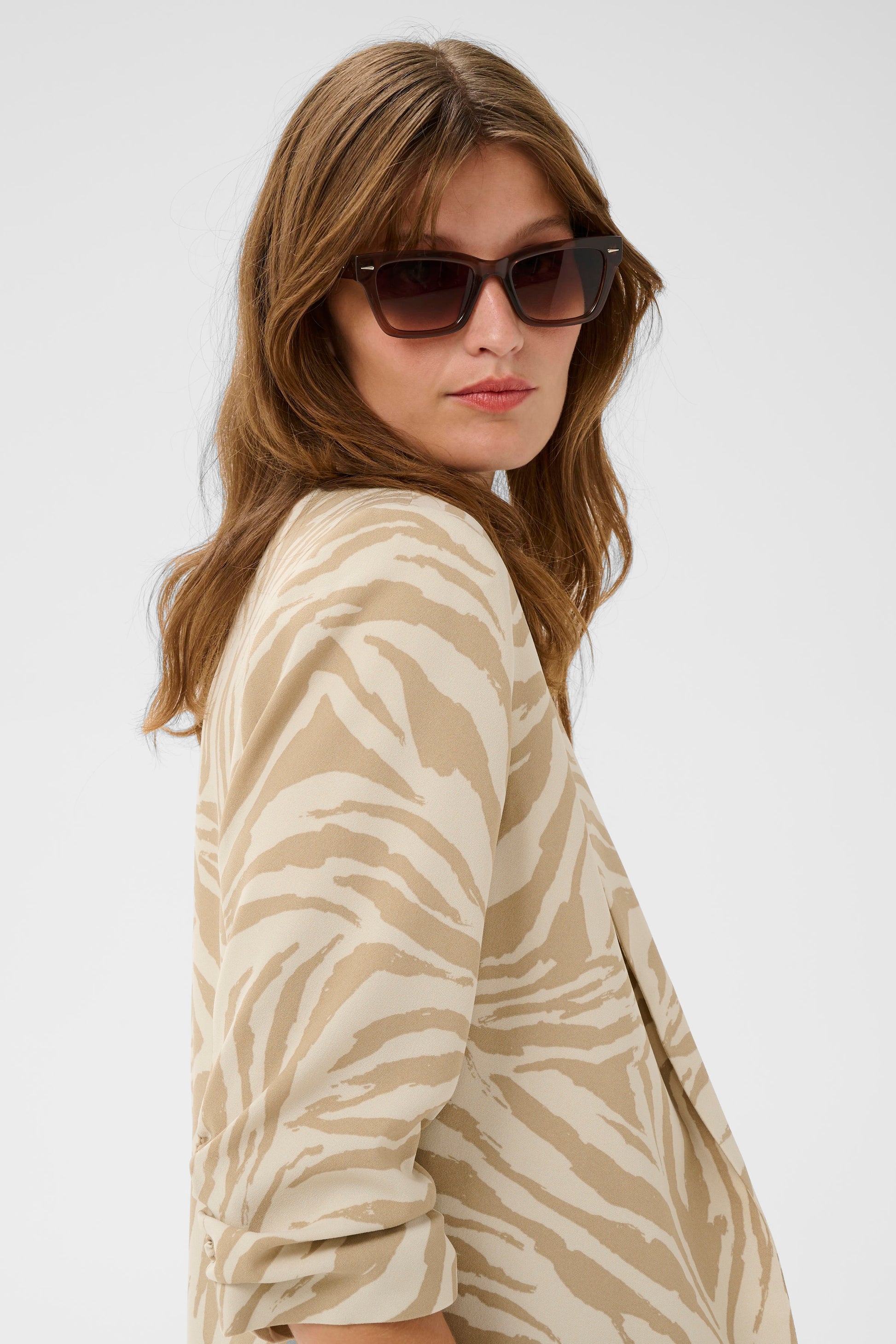 Woman wearing a beige and brown zebra print jacket on a white background