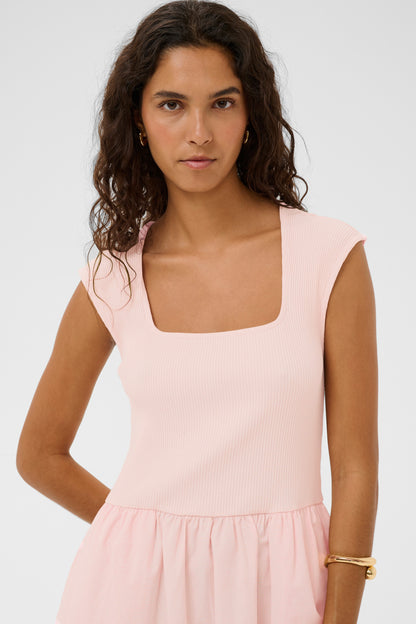 Woman wearing a light pink dress against a white background