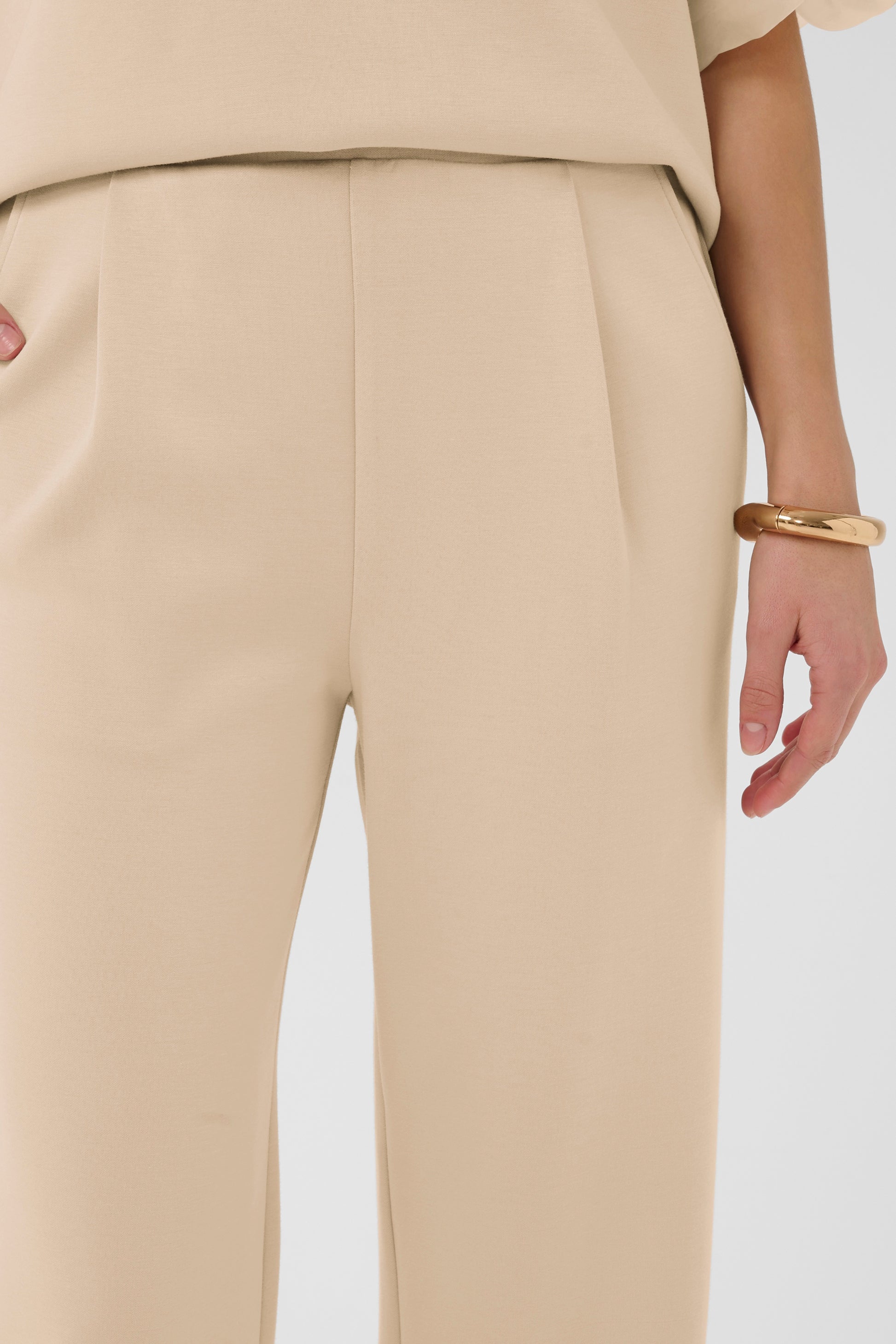 Beige pants worn by a person on a white background