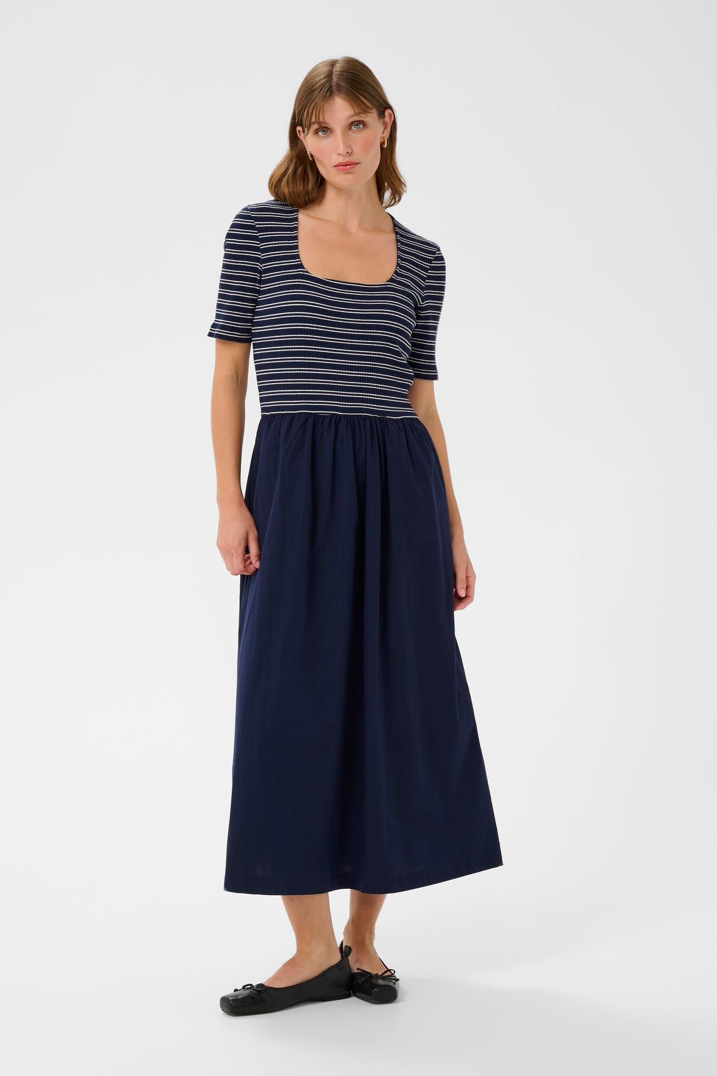Woman wearing a striped shirt and navy skirt on a white background