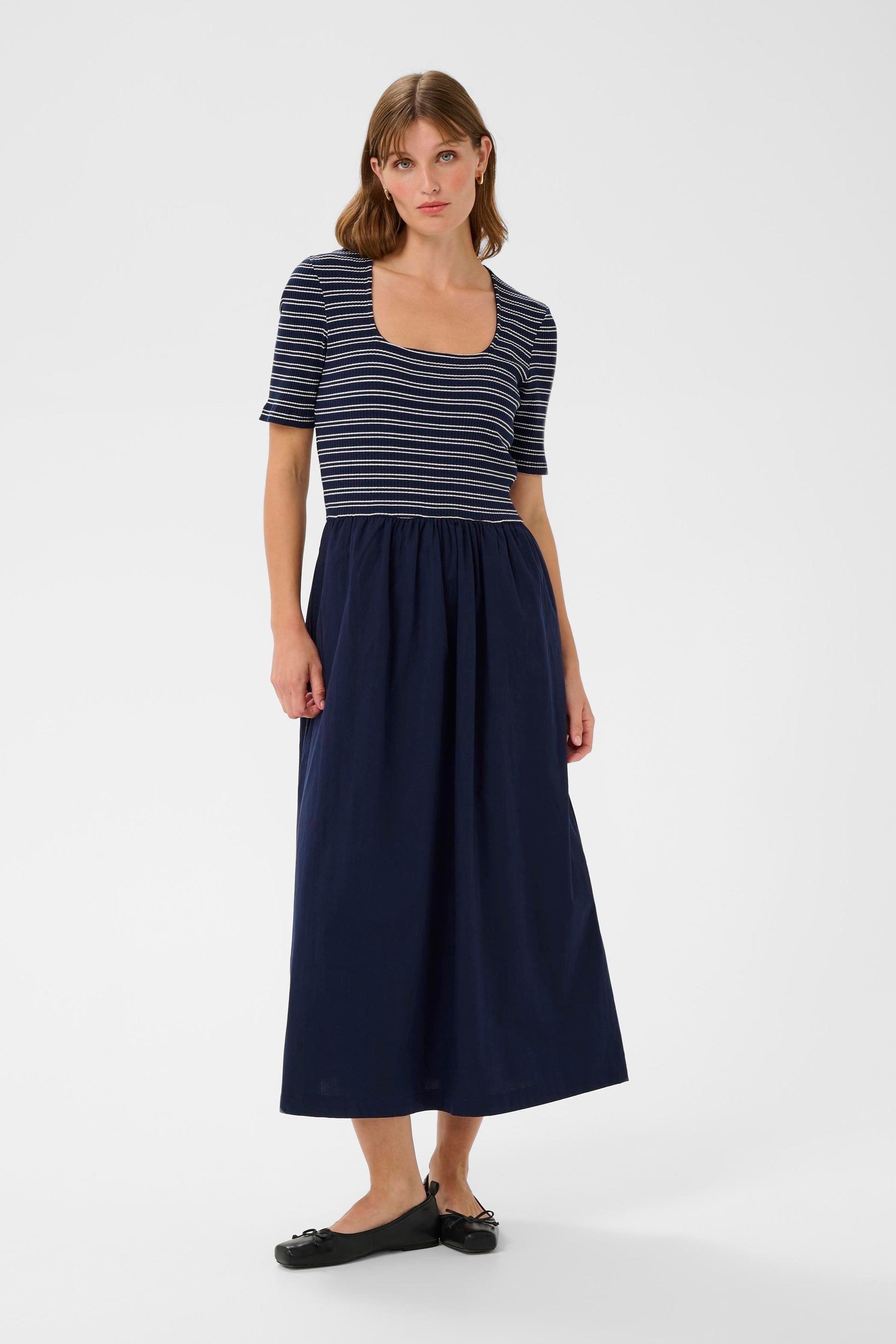 Woman wearing a striped shirt and navy skirt on a white background
