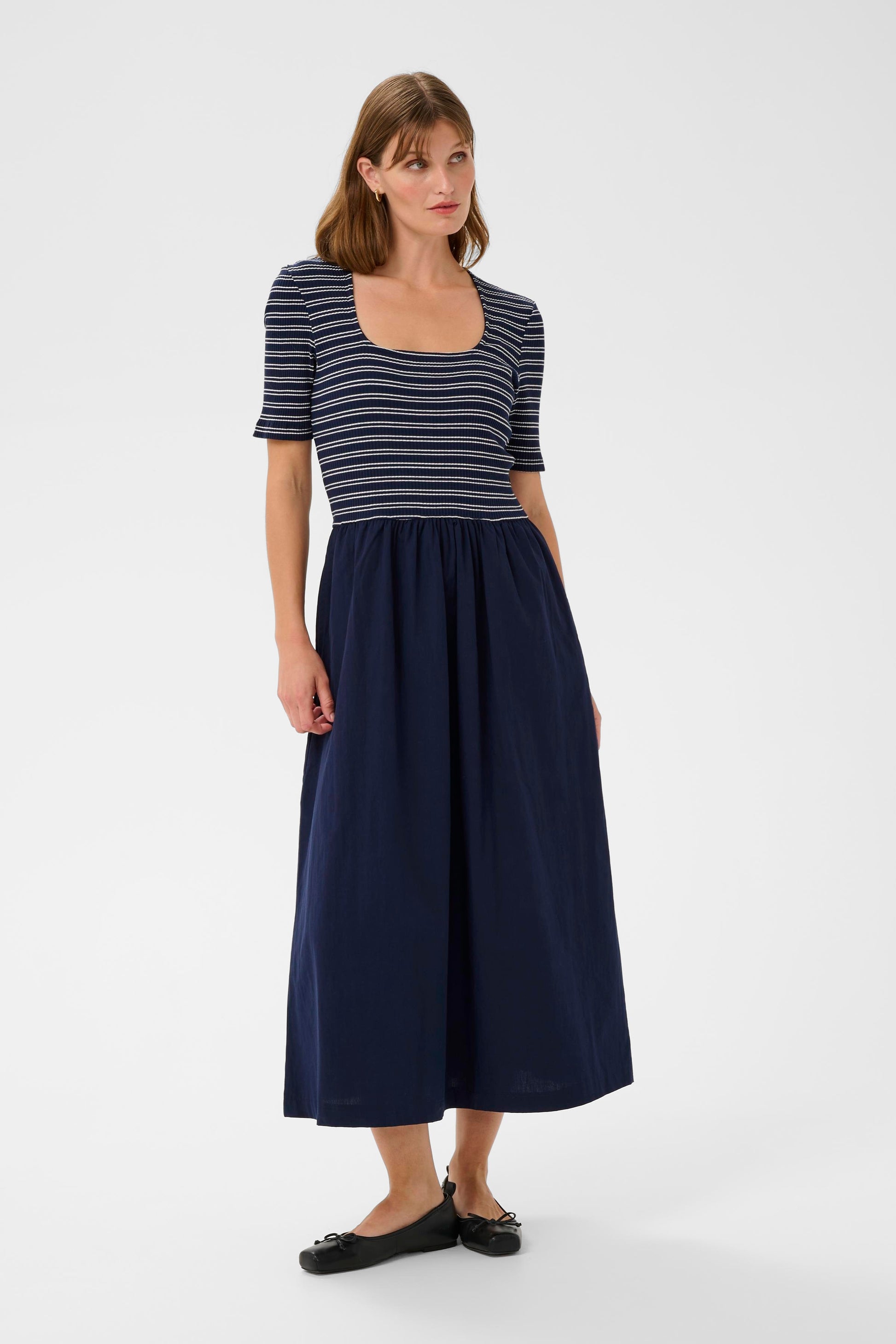 Woman wearing a striped top and navy skirt on a white background