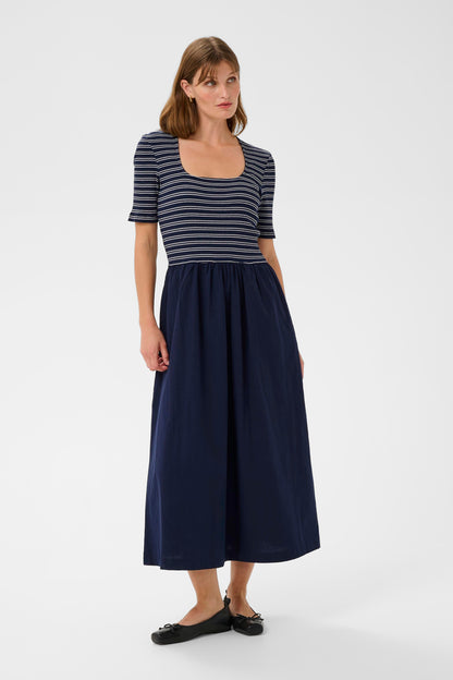 Woman wearing a striped top and navy skirt on a white background