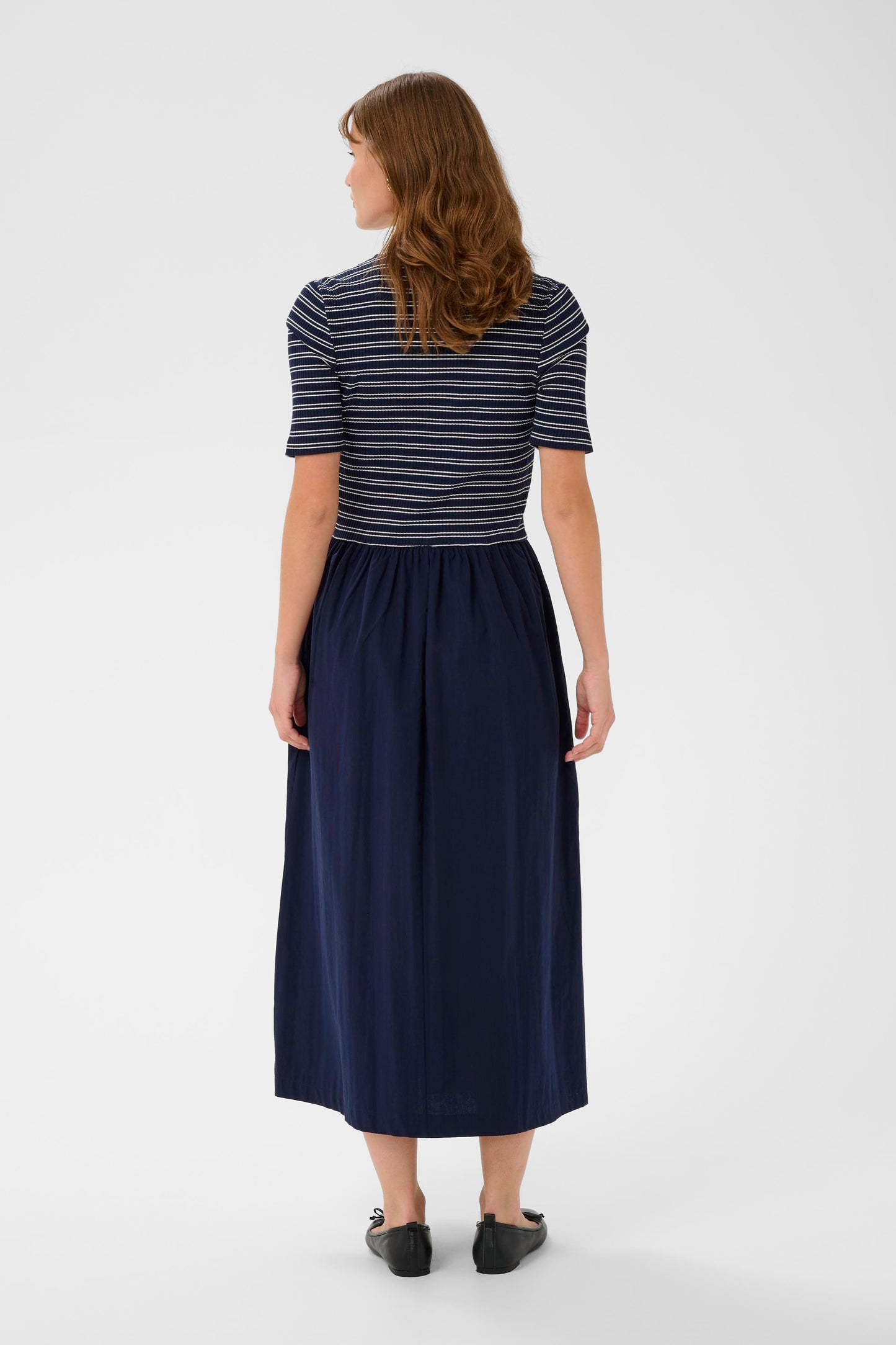 Woman wearing a striped shirt and navy skirt on a white background