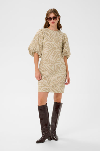 Woman wearing a patterned dress with puffed sleeves and brown knee-high boots on a white background