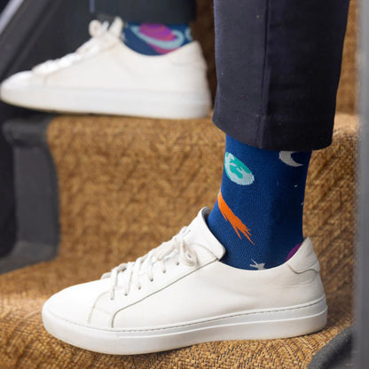 White sneakers with blue socks featuring colorful designs on a textured surface.