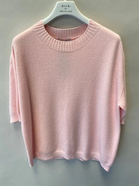 Pink sweater on a hanger against a gray background