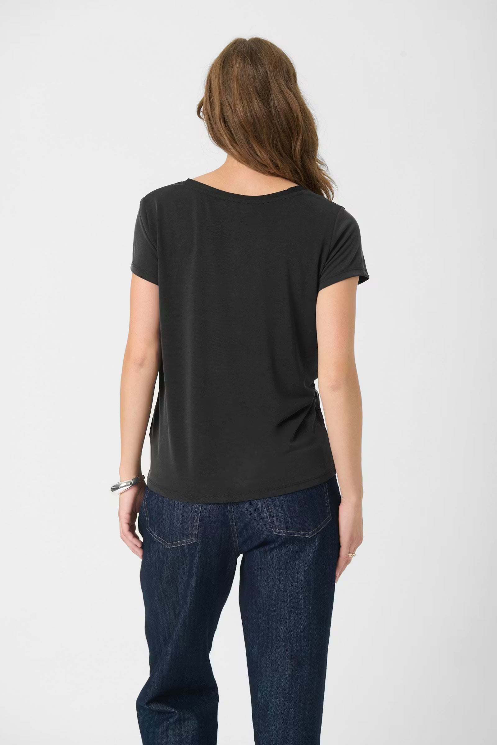 Person wearing a black t-shirt and blue jeans on a white background