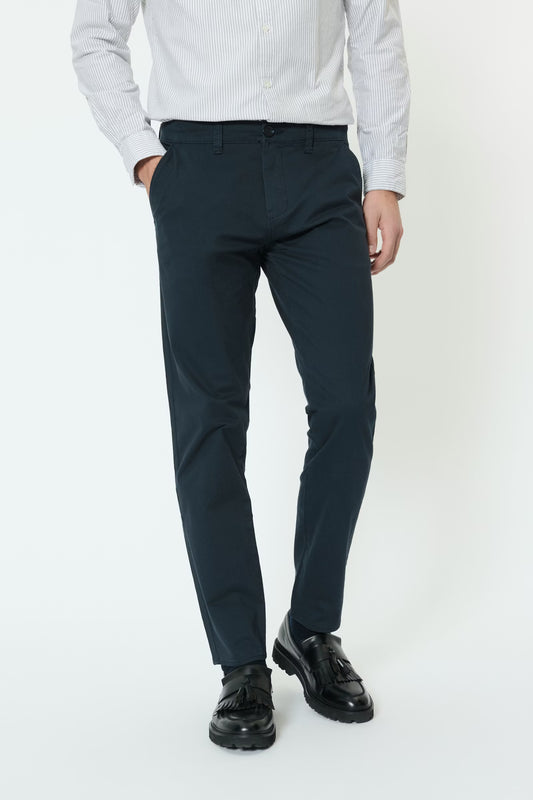 Person wearing navy pants and black shoes on a white background