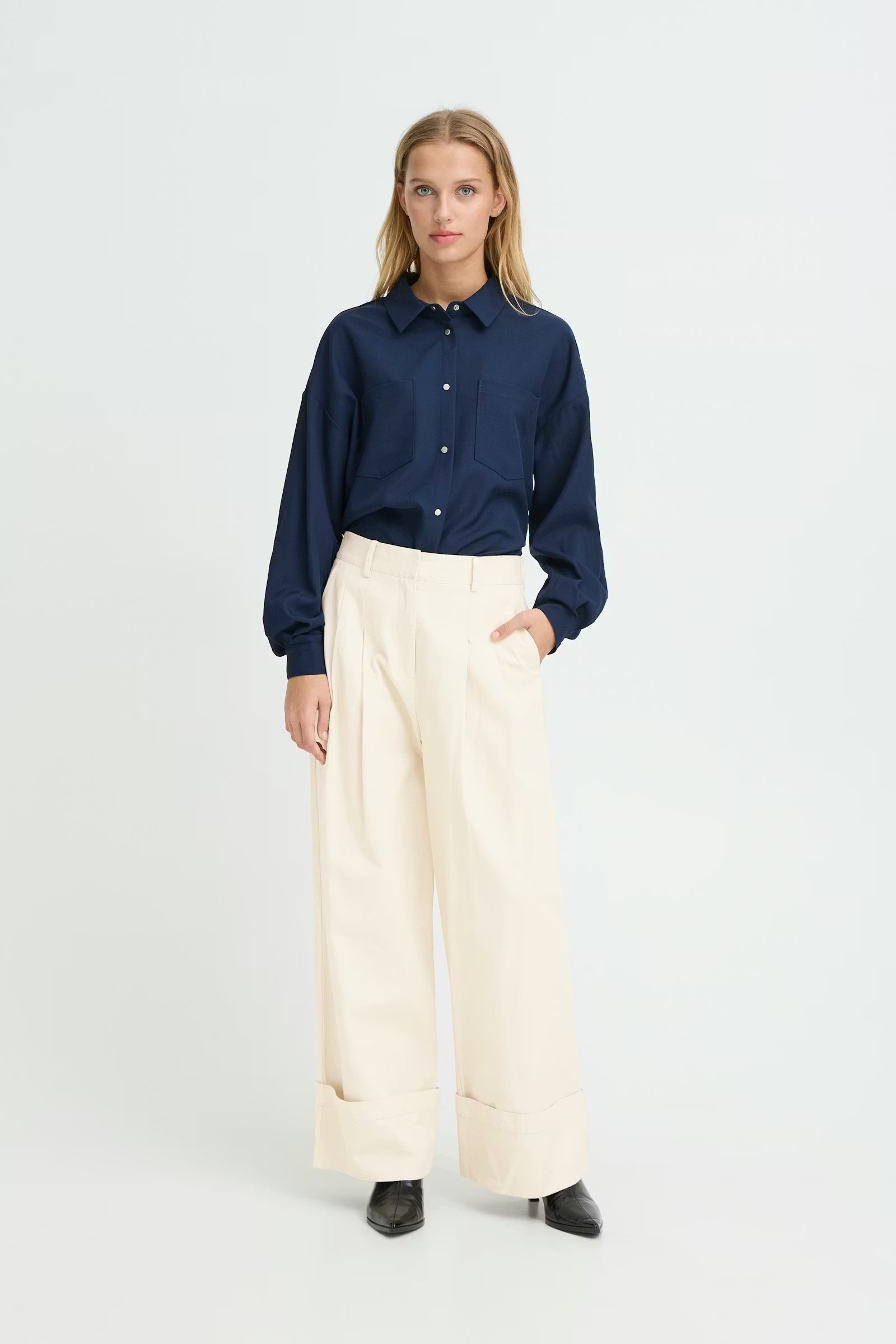 Women wearing cream trousers with navy shirt. White studio background