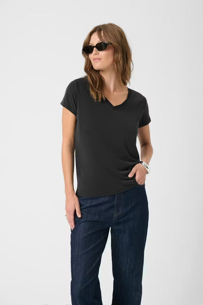 Woman wearing a black t-shirt and dark jeans on a white background