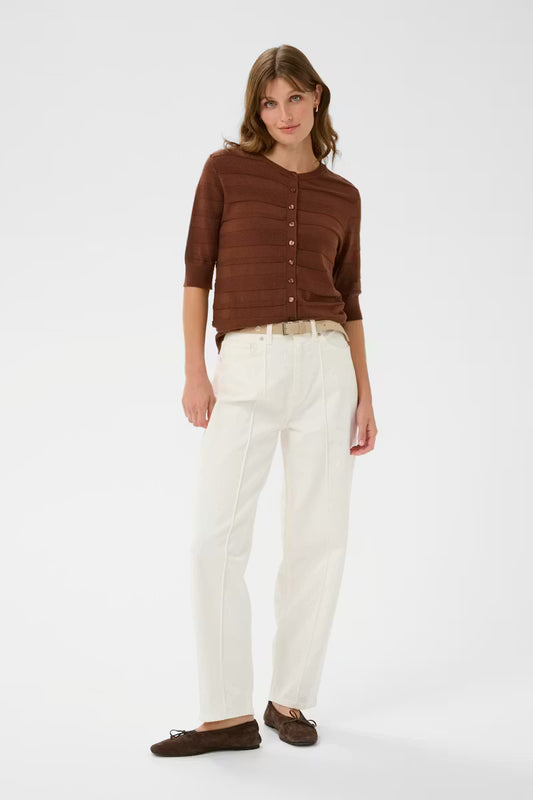 Woman wearing a brown button-up shirt and white pants on a white background