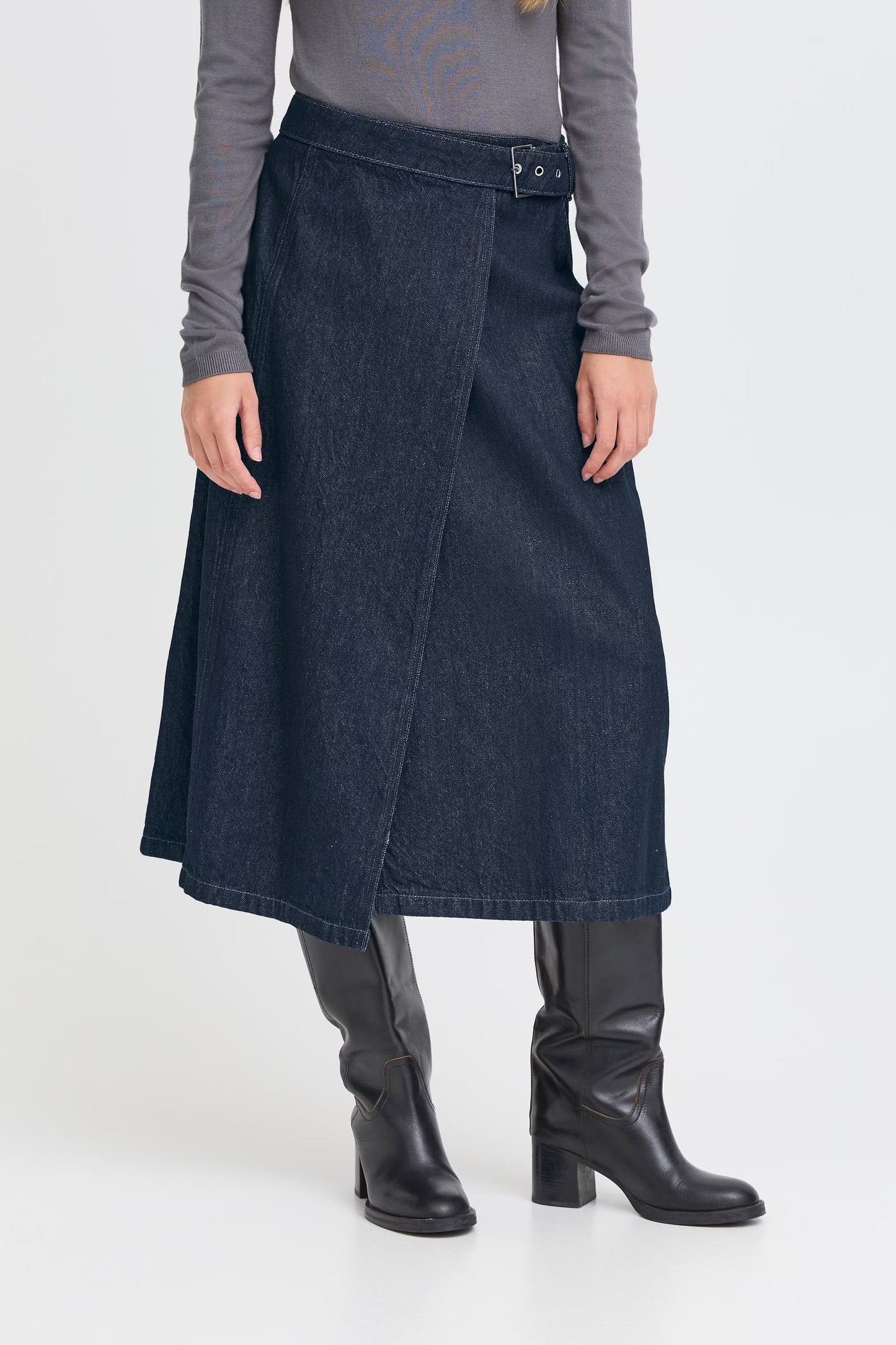 Person wearing a dark blue skirt and black boots on a white background