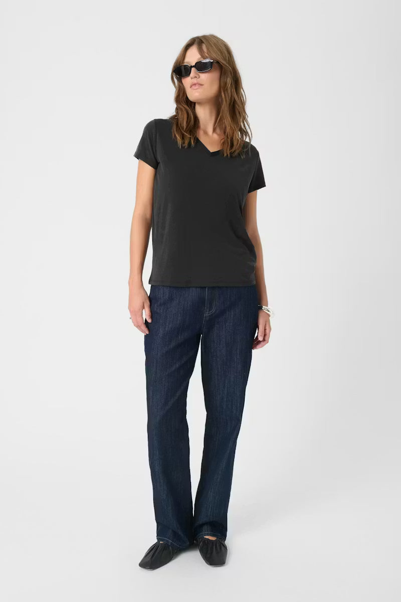 Woman wearing a black t-shirt and blue jeans on a white background