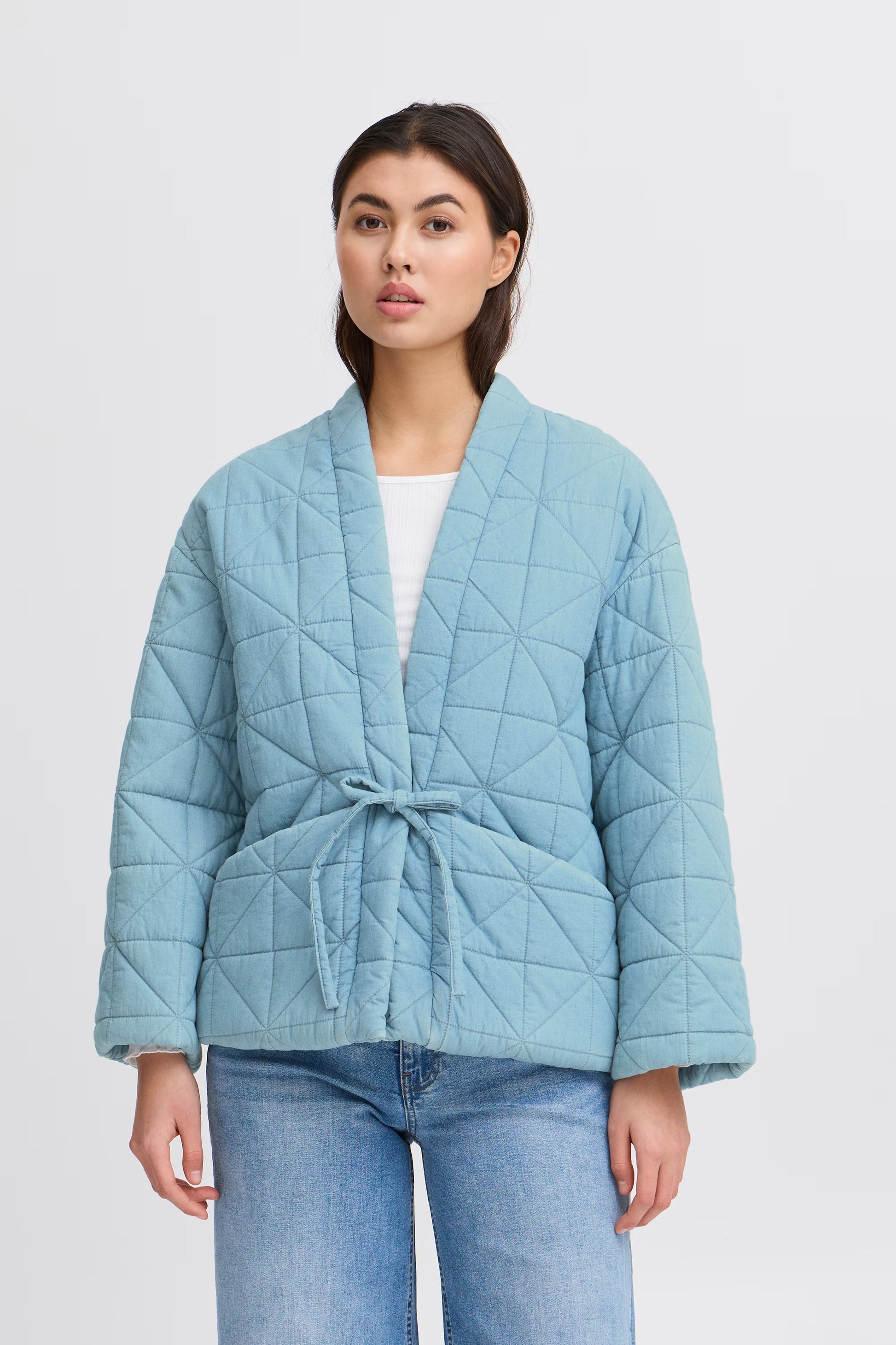Woman wearing a light blue quilted jacket on a white background