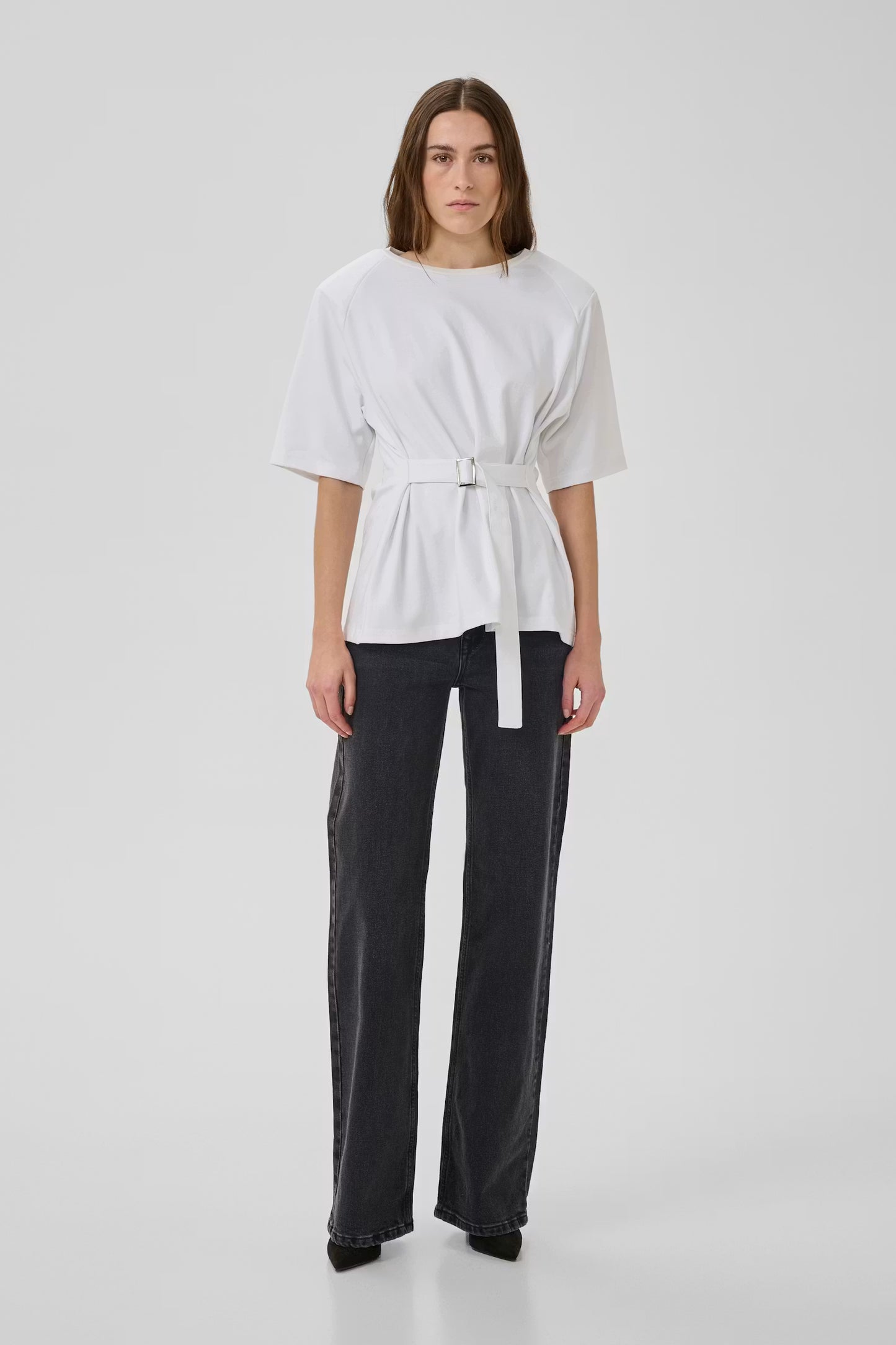 Person wearing a white top and black pants on a white background