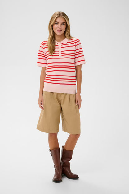 Woman wearing a red and white striped shirt, beige shorts, and brown boots on a white background