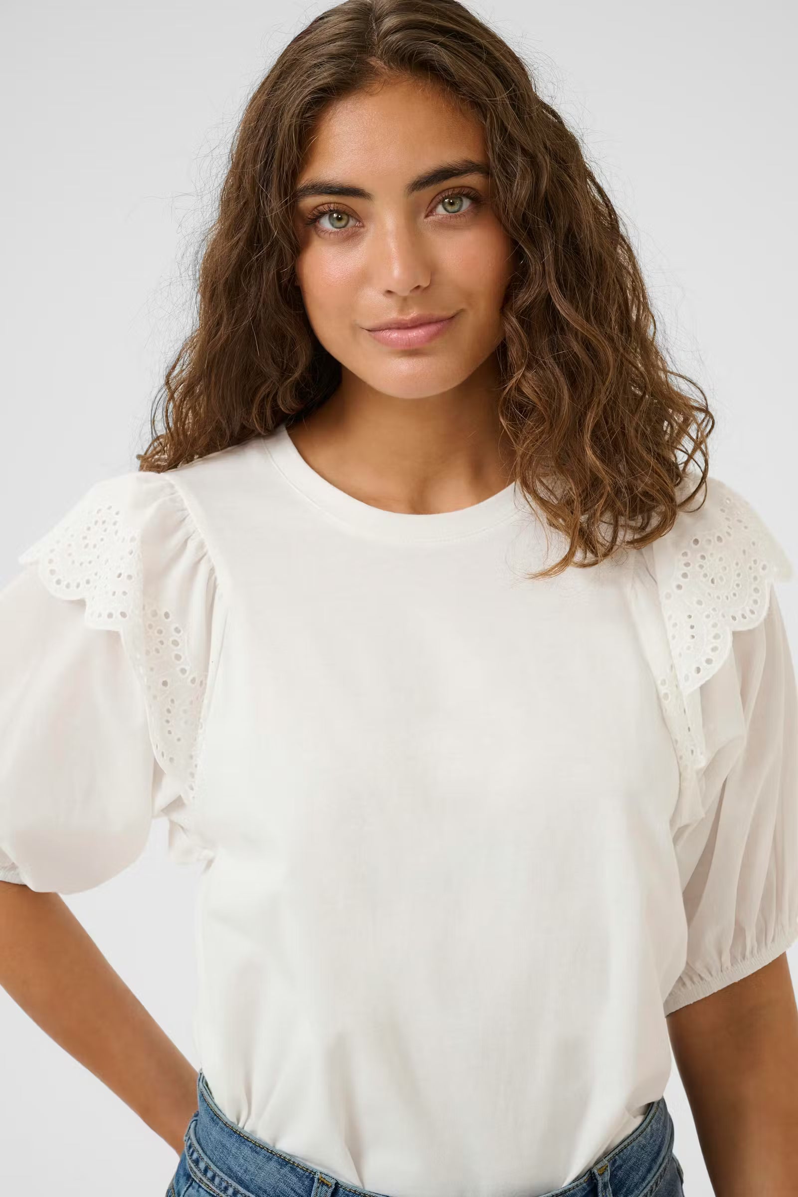 Woman wearing a white blouse with puffed sleeves against a plain background