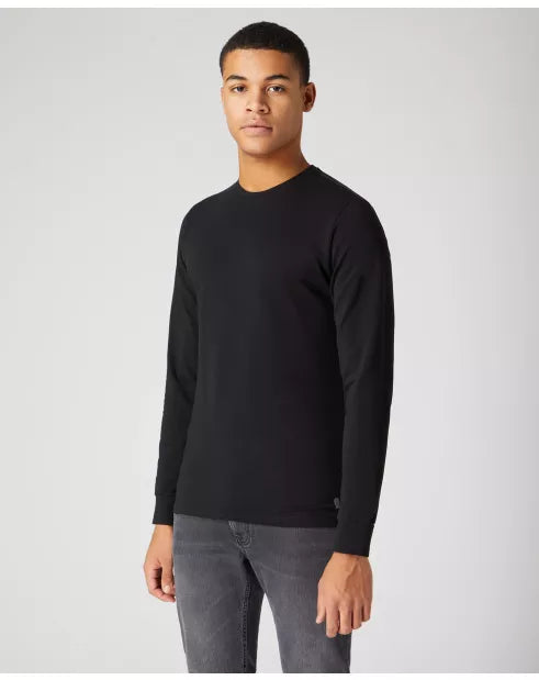 Man wearing a black long-sleeve shirt and gray pants on a white background