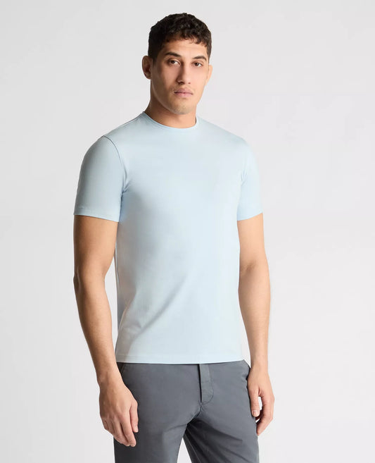 Man wearing a light blue t-shirt and gray pants on a plain background