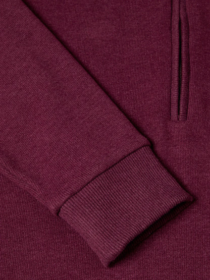 Close-up of a ribbed knit garment in a deep burgundy or plum purple color, showing the texture of the fabric and a portion of a vertical zipper.
