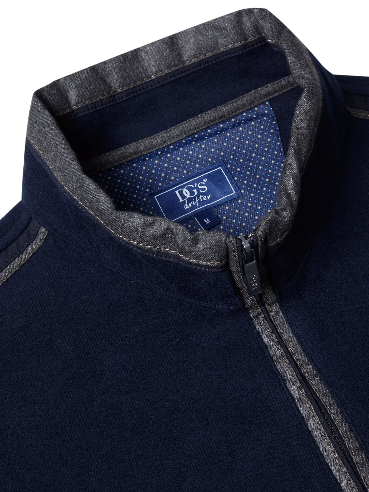 Close-up of a navy blue zip-up sweater with a gray ribbed collar and zipper trim, featuring a visible neck label that reads 'ICS design'.