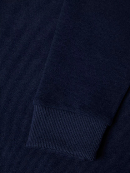Close-up of a dark navy ribbed knit fabric, showing the texture and cuff detail of a garment.