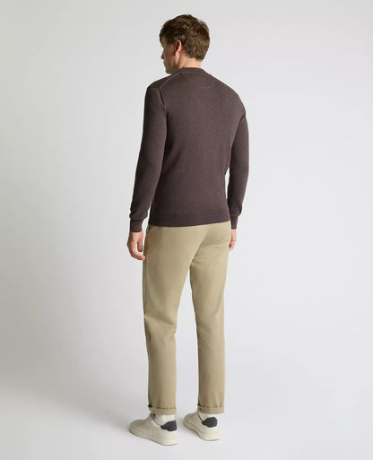 Man wearing a brown sweater and beige pants on a white background