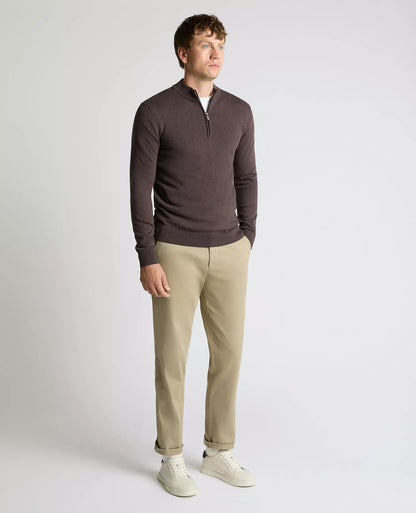 Man wearing a brown sweater and beige pants on a white background