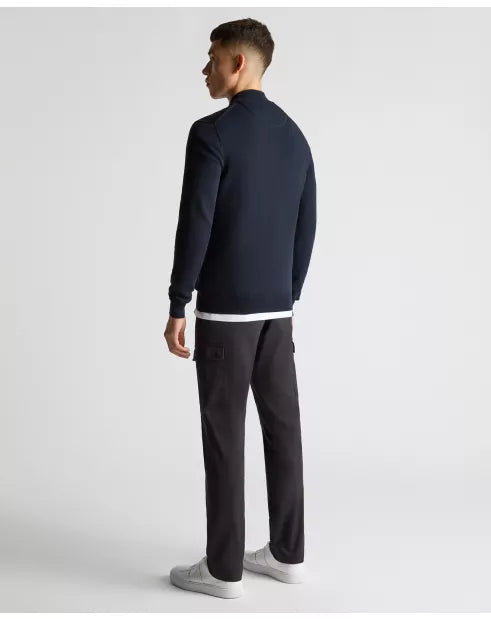 Man wearing a navy blue sweater and black cargo pants on a white background
