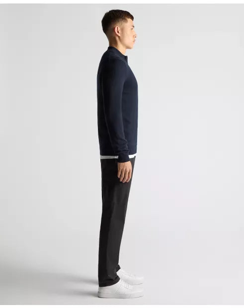 Man wearing a navy sweater and black pants on a white background